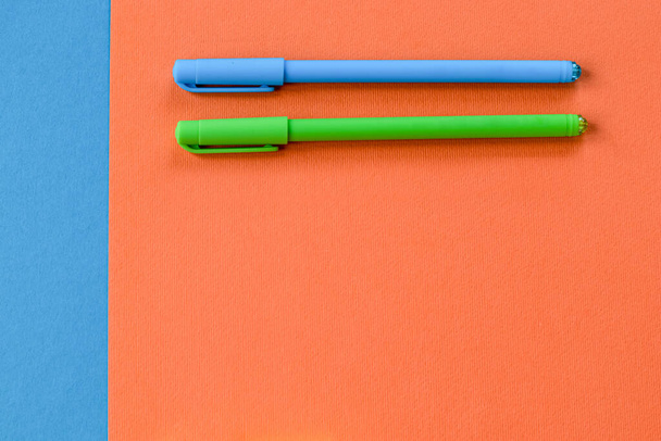 Minimum set of school and office supplies on bright orange and blue background. Two pens banner. Concept: back to school. Flatlay, top view. - Fotografie, Obrázek