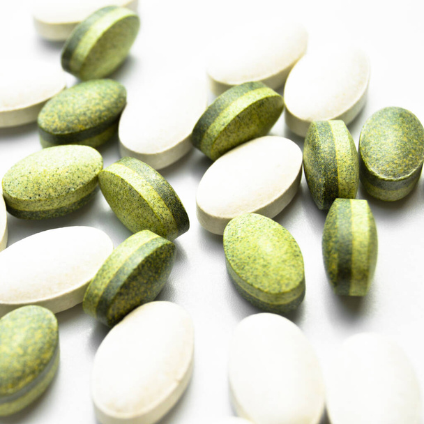 Witte en groene ovale tablet pillen geïsoleerd op witte achtergrond, medische ovale pillen tabletten - Foto, afbeelding