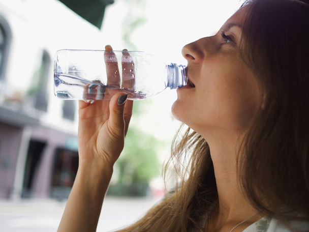 vrouw drinkwater uit een plastic fles - Foto, afbeelding