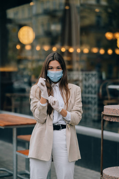 Νεαρή γυναίκα με μάσκα προσώπου στο δρόμο - Φωτογραφία, εικόνα