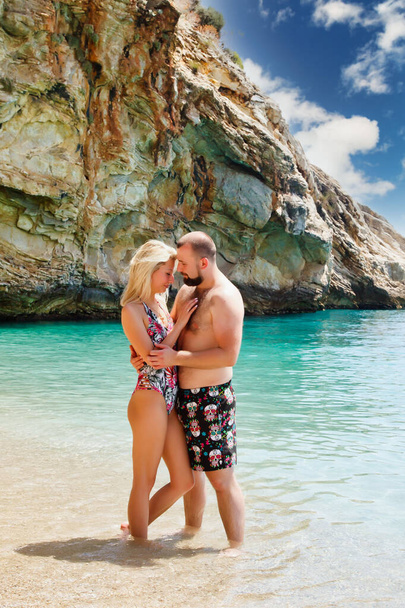 Loving couple enjoying honeymoon on beach in laguna with luxury view walking on sea background. Happy lovers on romantic trip have fun on summer vacation. Concept romance and relaxation. Copy space - Valokuva, kuva