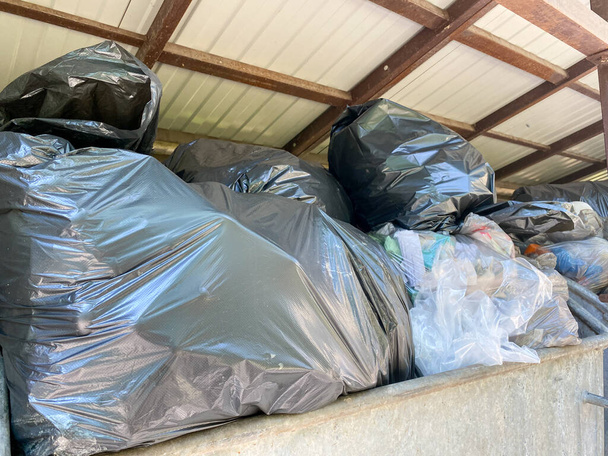 Οι σακούλες με τα σκουπίδια είναι στο δοχείο απορριμμάτων. Πολλά σκουπίδια πετάχτηκαν σε κοντέινερ. - Φωτογραφία, εικόνα