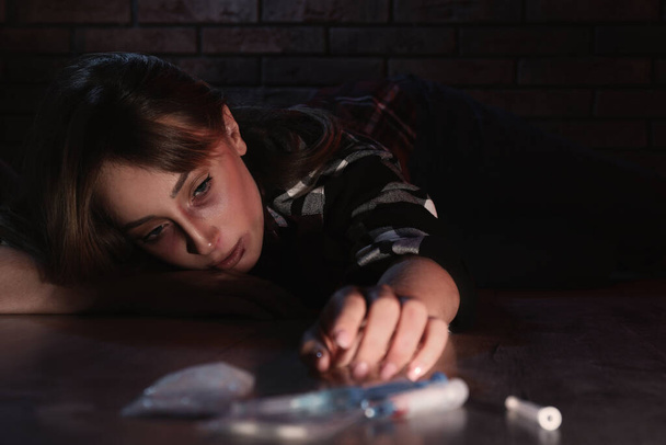 Addicted woman near different drugs on floor - Фото, изображение