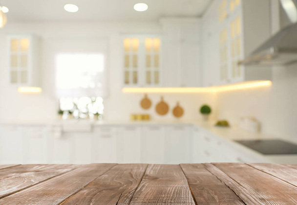 Empty wooden table and blurred view of stylish kitchen interior. Mockup for design - Foto, afbeelding