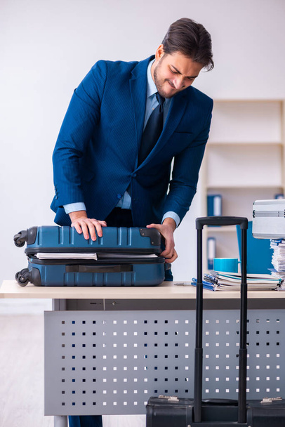 Young male employee preparing for business trip at workplace - Photo, image