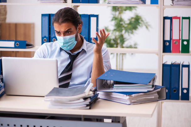 Молодой работник, работающий в офисе во время пандемии - Фото, изображение