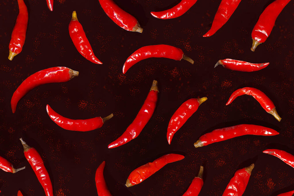 Seamless pattern with red chili peppers on a dark background. - Photo, Image