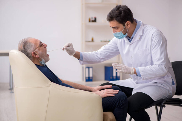 Old male patient visiting young male doctor otorhinolaryngologis - Zdjęcie, obraz