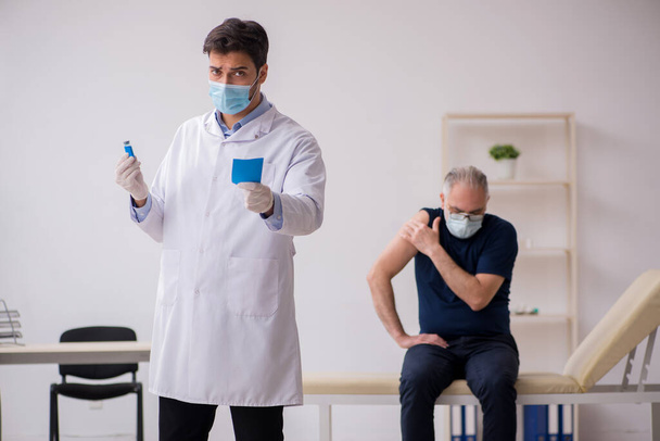 Alte männliche Patientin besucht jungen männlichen Arzt im Impfpass - Foto, Bild