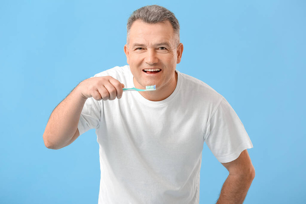 Érett férfi fogmosás fogmosás színes háttér - Fotó, kép