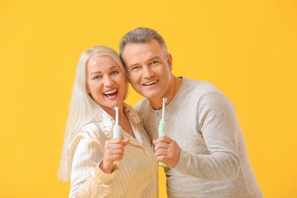 Volwassen paar met tandenborstels op kleur achtergrond - Foto, afbeelding