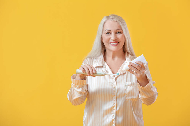 Reife Frau beim Zähneputzen auf farbigem Hintergrund - Foto, Bild