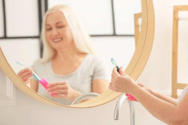 Femme mature brossant les dents à la maison - Photo, image