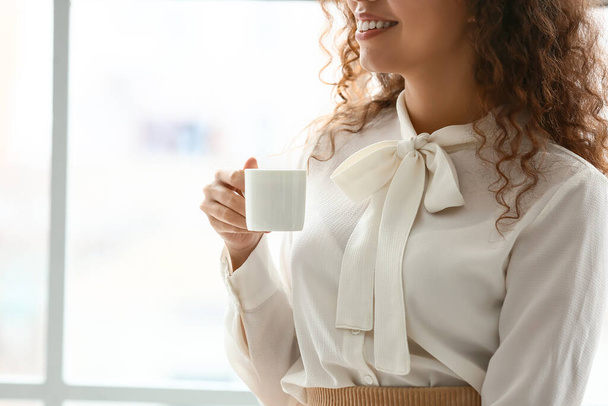 Beautiful young woman drinking coffee in office - 写真・画像