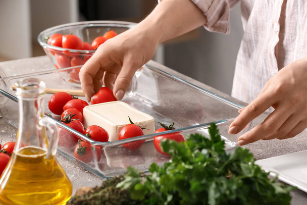 Nainen valmistelee tomaatteja ja fetajuustoa leivontaan keittiössä - Valokuva, kuva