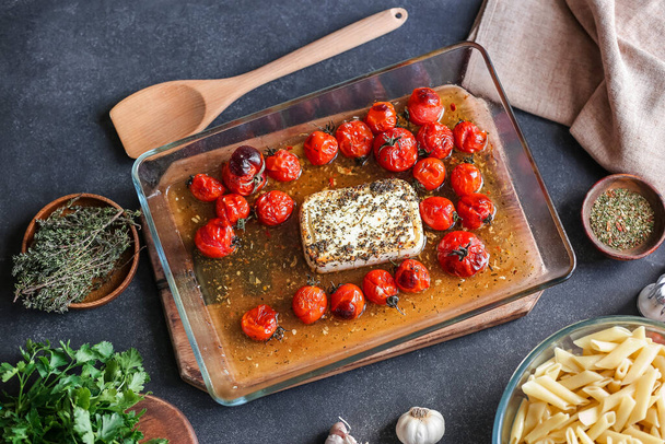 Baking dish with roasted tomatoes, feta cheese and spices on dark background - Fotoğraf, Görsel
