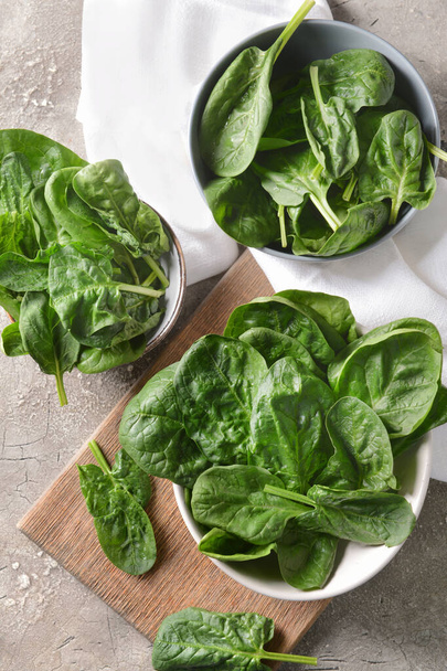 Bowls with fresh spinach leaves on grunge background - Photo, Image