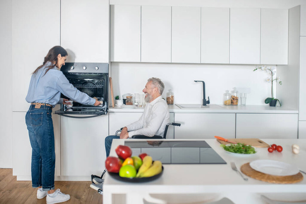 Gray-haired handicapped man and his young wife in the kitchen getting the breakfast ready - Fotoğraf, Görsel