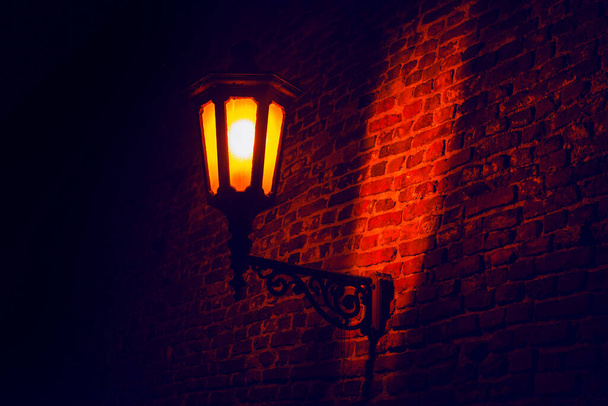 Ortaçağ sokak ışığı aydınlatması. Sokak lambası ve tuğla duvar. Eski kentte aydınlanma  - Fotoğraf, Görsel