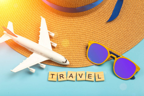 Utazás nyári háttér. Napszemüveg, kalap, repülőgép és strandkiegészítők színes kék háttérrel. Turista nyaralás, pihenés és nyári koncepció. - Fotó, kép