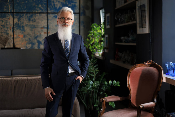 Stylish bearded man in a suit standing in modern office - Foto, Imagem