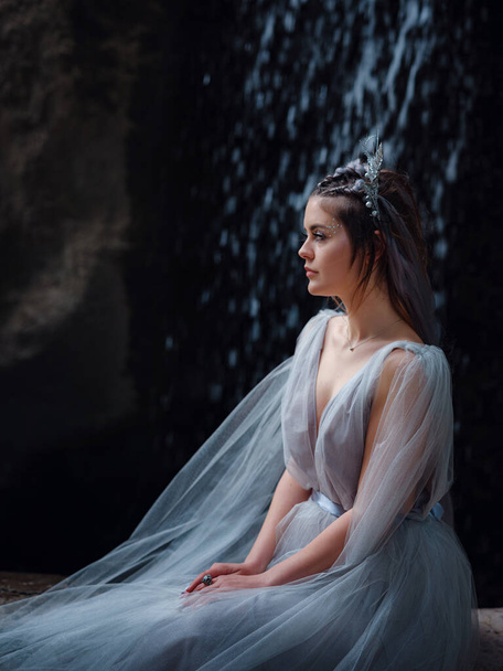 a beautiful woman like a fairy or nymph walking in the park. fairy tale image art photo. beautiful portrait in the darkness of the park, the waterfall jets like wings - Foto, Imagem