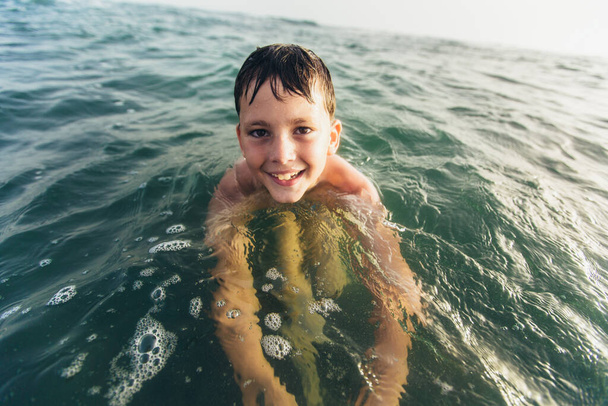 海で遊ぶ幸せな子供。子供は屋外で楽しんでいる。夏休みと健康的なライフスタイルのコンセプト。選択的焦点 - 写真・画像