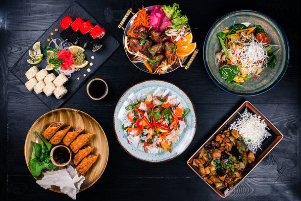 Asian food cooking. Wok, noodles and vegetables salad and chopsticks on dark rustic background - Foto, Imagem