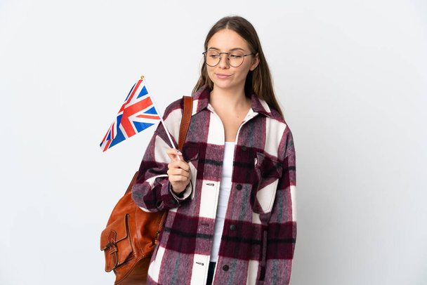 Junge Litauerin mit einer britischen Flagge auf weißem Hintergrund, die Zweifel hat, während sie Seite sieht - Foto, Bild