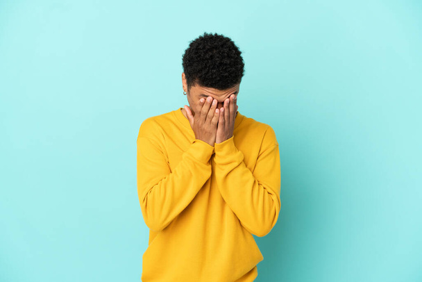 Young African American man isolated on blue background with tired and sick expression - Photo, Image