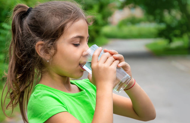Παιδί κορίτσι πίνει νερό από ένα ποτήρι. Επιλεκτική εστίαση. Παιδί. - Φωτογραφία, εικόνα