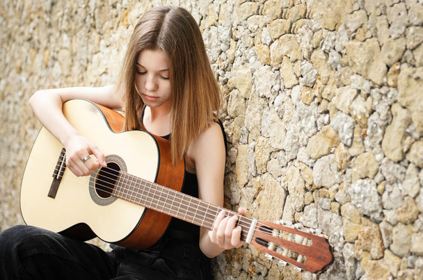 Teini tyttö kitara vastaan ruskea seinä - Valokuva, kuva