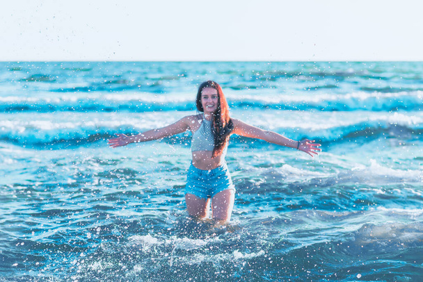 Young woman playing in the sea in summer. woman enjoying in sea water.Cheerful young woman having fun on the beach. She is relaxed in the sea water and enjoys on vacation. - 写真・画像