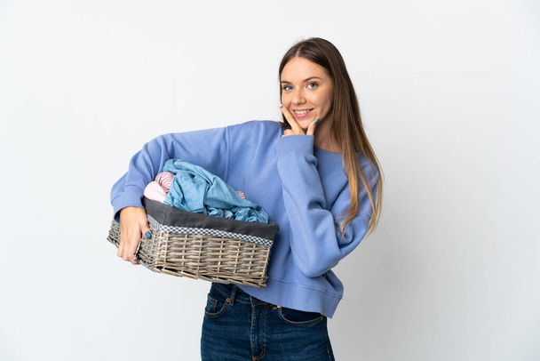 Young Lithuanian woman holding a clothes basket isolated on white background happy and smiling - Photo, image