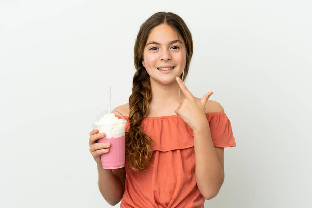 mały kaukaski dziewczyna z truskawkowy milkshake odizolowany na biały tło dając kciuki w górę gest - Zdjęcie, obraz