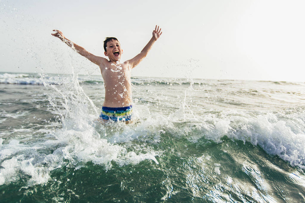 Onnellinen lapsi leikkii meressä. Lapsella on hauskaa ulkona. Kesäloma ja terveellisten elämäntapojen käsite. Valikoiva painopiste - Valokuva, kuva