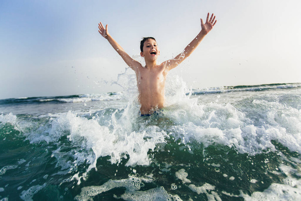 Glückliches Kind, das im Meer spielt. Kinder haben Spaß im Freien. Sommerurlaub und gesundes Lebensstil-Konzept. Selektiver Fokus - Foto, Bild