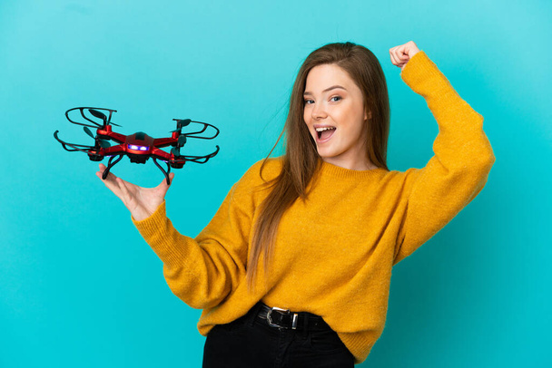 Teini tyttö tilalla drone yli eristetty sininen tausta juhlii voittoa - Valokuva, kuva