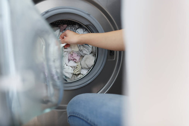 Frau zieht saubere Kleidung aus Waschmaschine in Badezimmer-Nahaufnahme - Foto, Bild