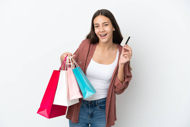 Joven francesa aislada sobre fondo blanco sosteniendo bolsas de compras y una tarjeta de crédito - Foto, imagen