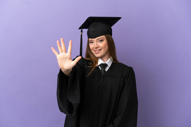 Giovane laureato su sfondo viola isolato contando cinque con le dita - Foto, immagini