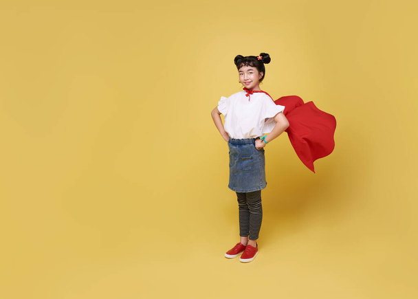 Kleines asiatisches Mädchen spielt Superheldin auf gelbem Hintergrund. Girl-Power-Held-Konzept. - Foto, Bild