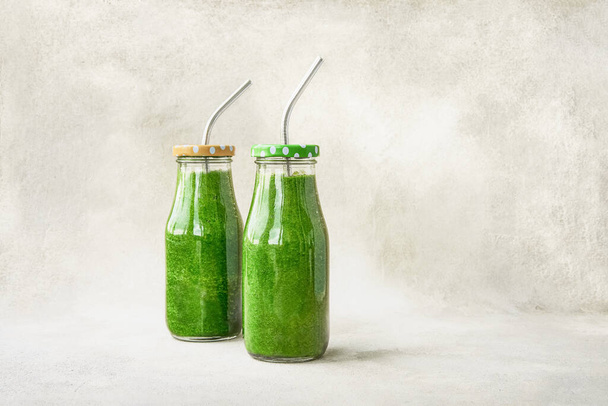 Frullato di spinaci verdi in piccole bottiglie su fondo chiaro. Stile di vita sano concetto - Foto, immagini