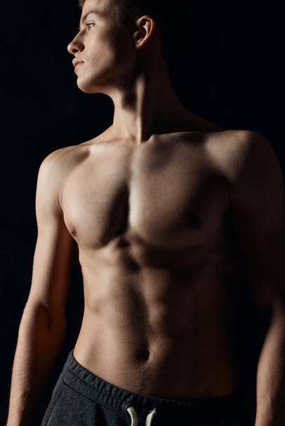athlete with a naked torso looking to the side on a black background cropped view - Foto, afbeelding