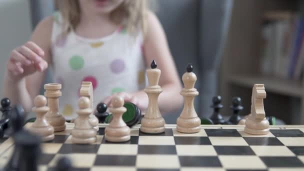 Holčička dává šachové figurky na tabuli, soustředí se na figurky, dítě je rozmazané - Záběry, video