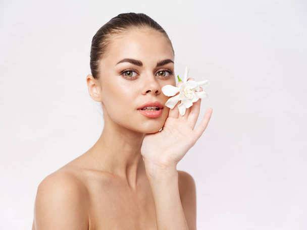 mujer bonita cosméticos hombros desnudos flor blanca piel clara - Foto, Imagen