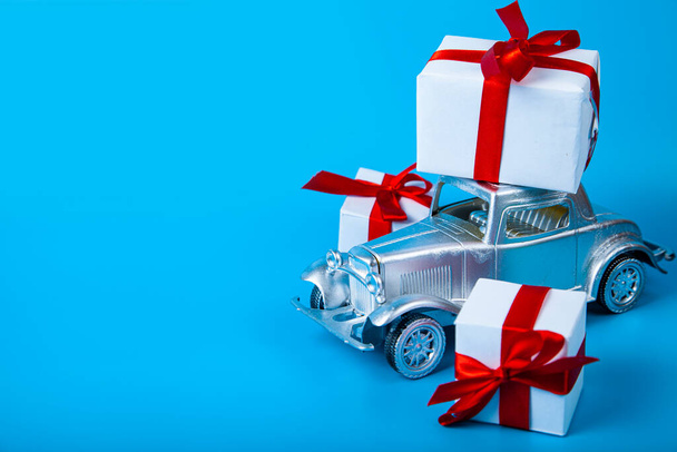 Silver car with gifts on a blue background. Buying a car. - Foto, Bild
