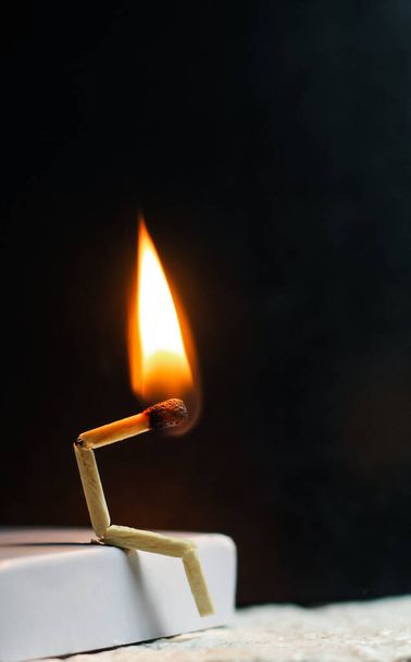 Concept of weakness, sadness, and loneliness. Image of a man-made matchstick. Burning matchstick man sitting alone without a partner. Matchstick art photography. - Photo, Image