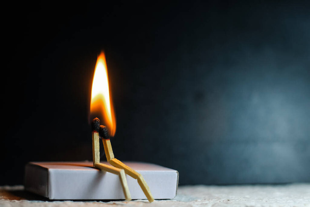 Two matches burning sitting together on the matchbox in the dark copy space. Two matches in flame as a metaphor of togetherness friendship, Love And Romance Concept. Matchstick art photography. - Photo, Image