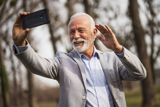 Щасливий старший бізнесмен розслабляється після роботи. Він обмін повідомленнями на смартфоні
. - Фото, зображення